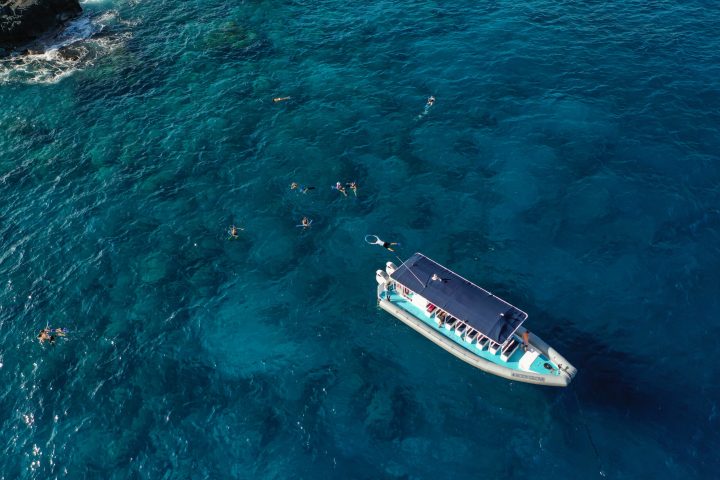 a boat floating in the bay with snorkelers